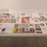 Stickers, 2010-2018. Stickers on a table inside glass cabinet:. Table 75x135x90cm; Glass cabinet, 15x135x90cm.